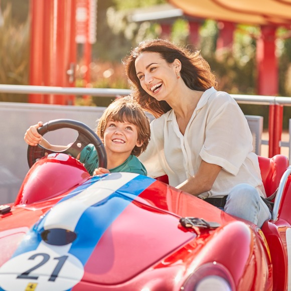 Madre e hijo disfrutando en una atracción infantil de Ferrari Land